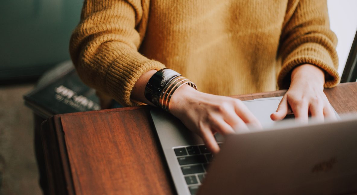 Close-up van een hogeschoolstudente die op een laptop werkt. Gezicht niet zichtbaar.