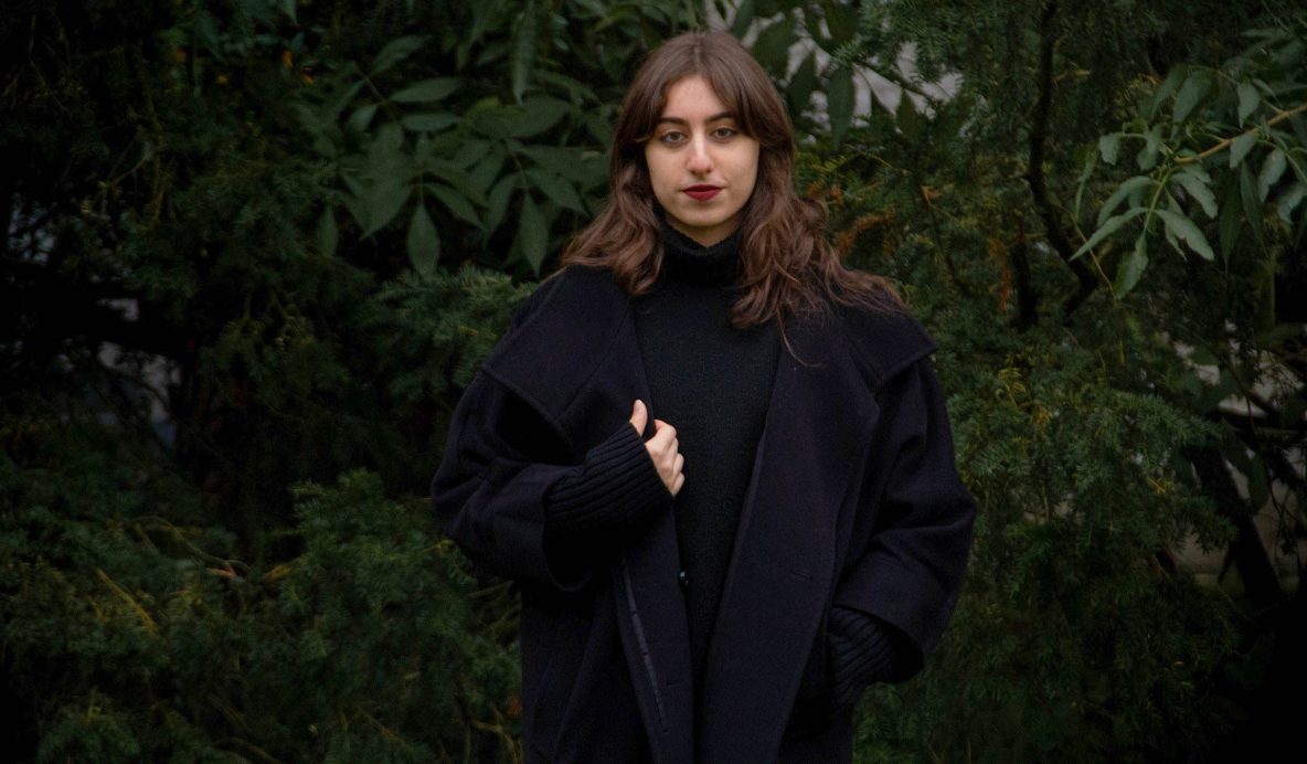 Elene Sainishvili, a 19 year old woman is posing in front of some plants.