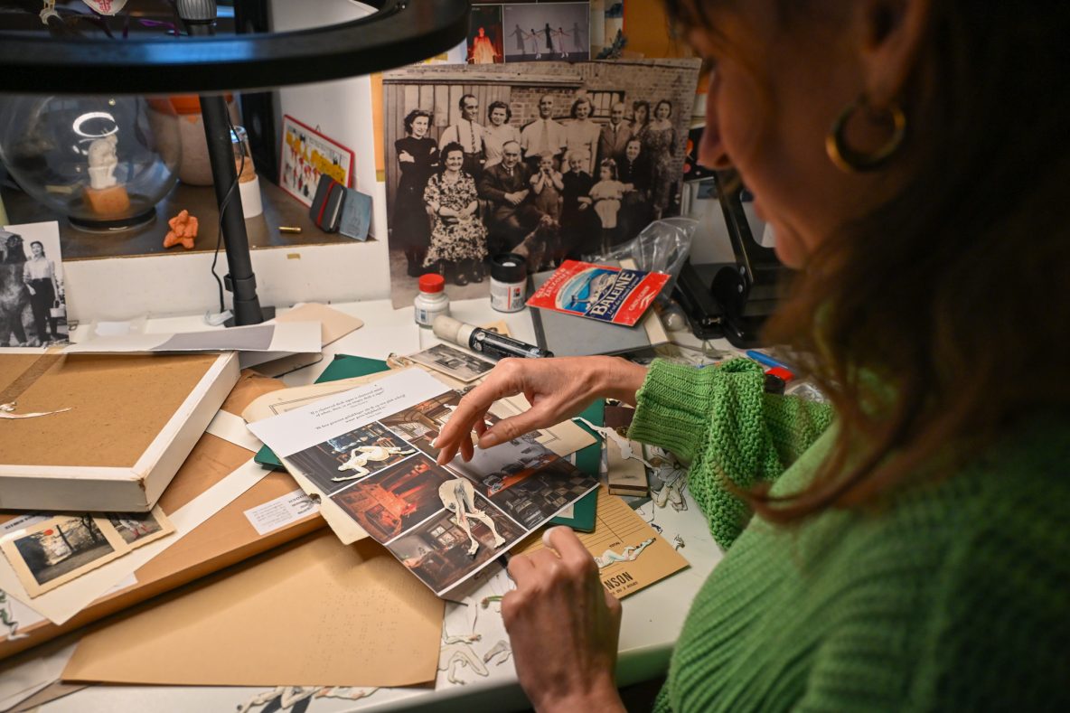 An artist at her desk, playing around with clippings of model drawing to make a collage